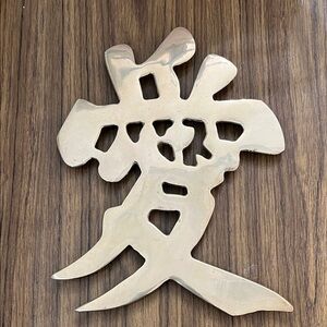 Vintage brass item is a collectible Chinese character wall hanging or trivet